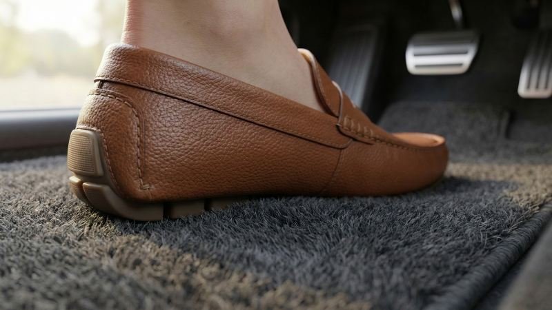 Driver shoe resting on cushioned car mat side view